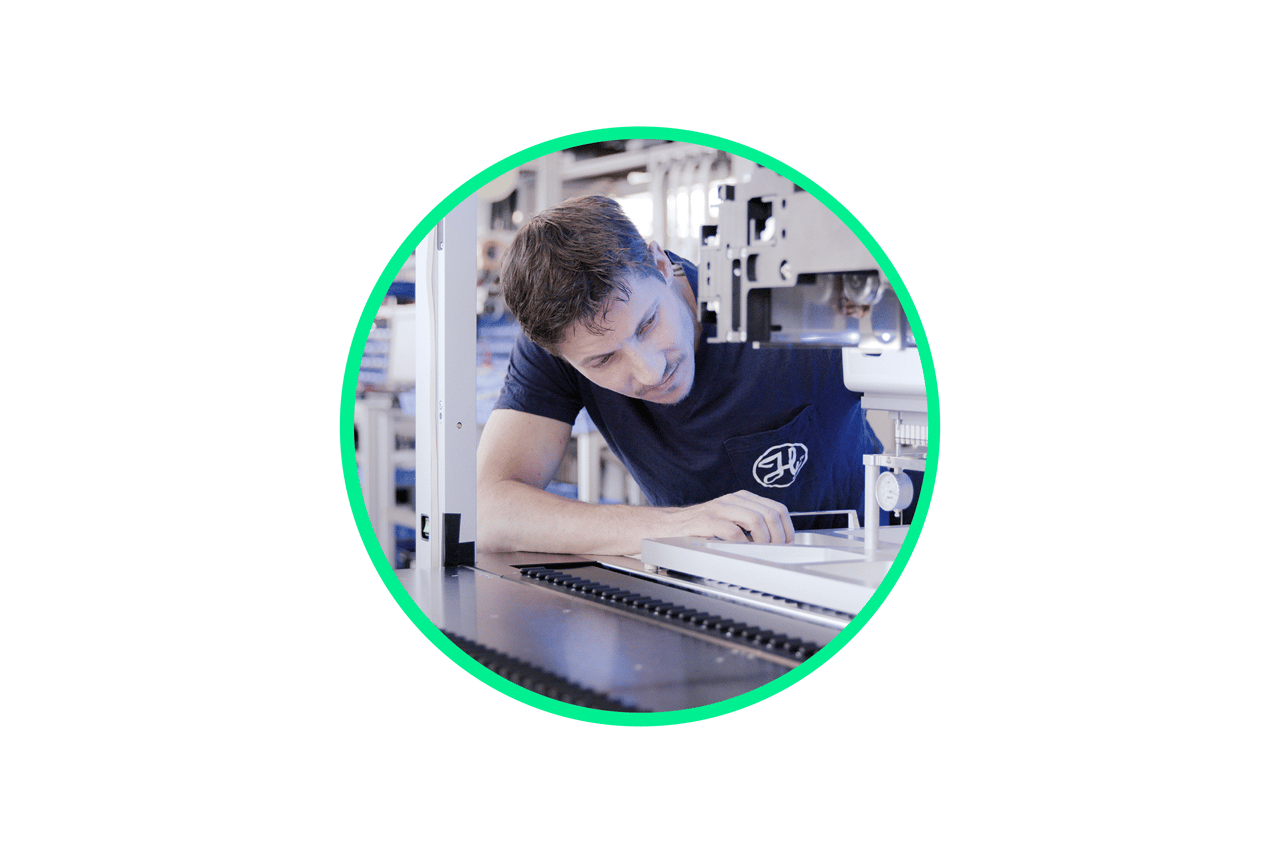 Technician inspecting a component on precision manufacturing equipment in a workshop