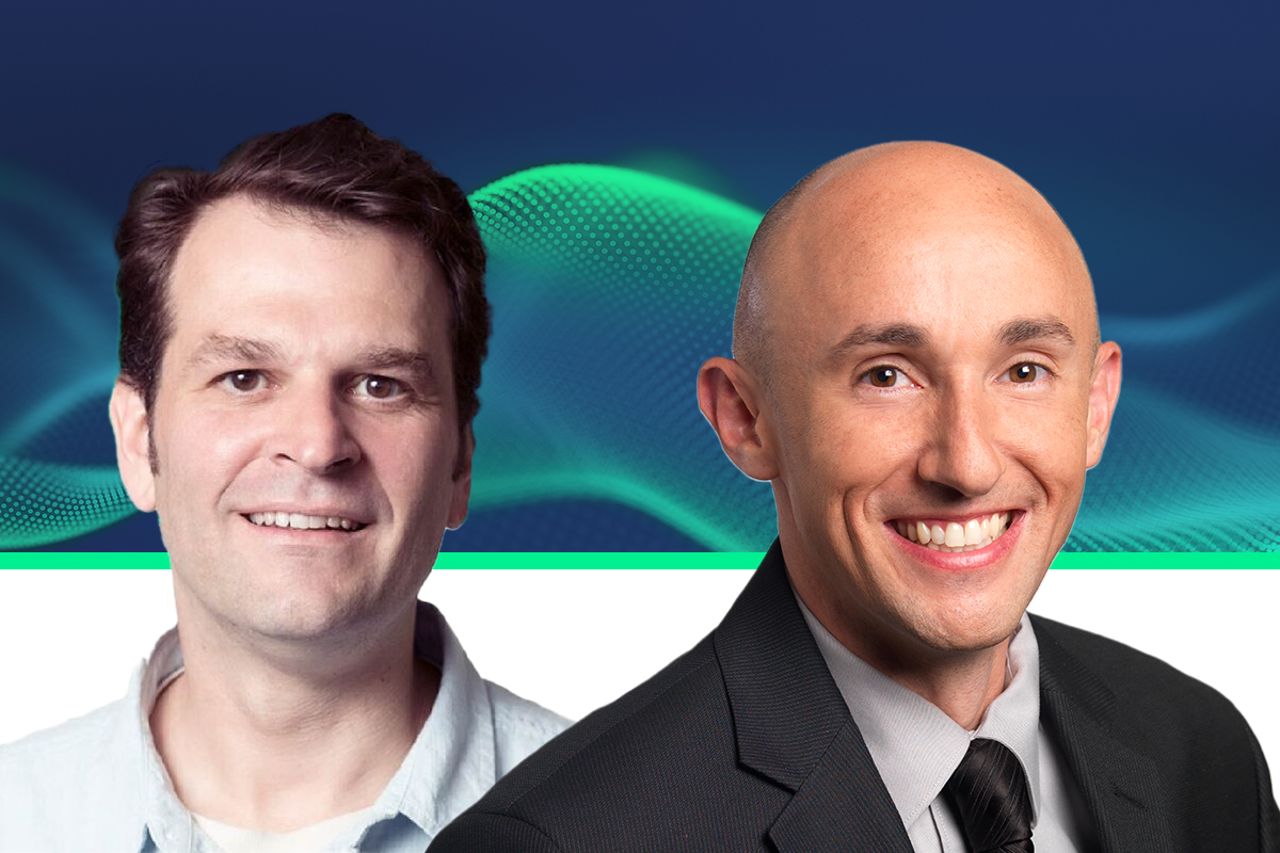 Two people smiling, one with dark hair in a casual shirt, one bald in a suit and tie, against a dark blue background with teal wave graphics.