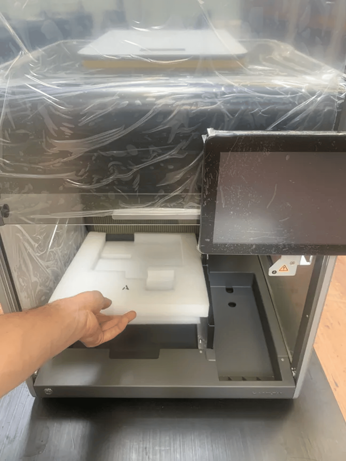 Hand removing foam packaging insert from an automated laboratory instrument with touchscreen display