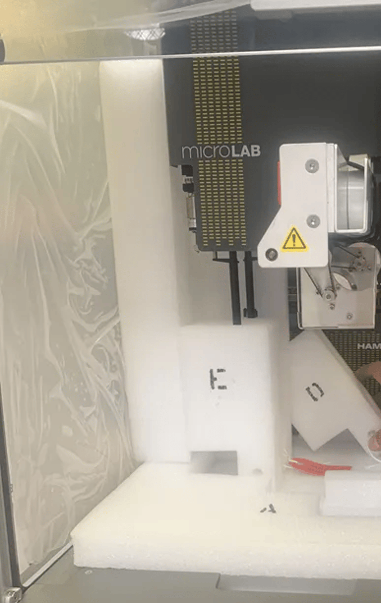MicroLAB automated liquid handling module with robotic arm, partially unboxed in foam packaging
