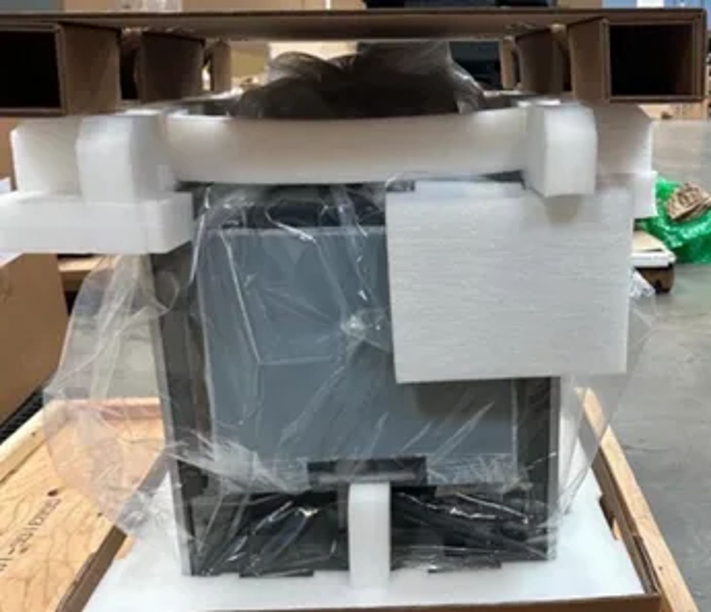 Packaged laboratory instrument secured in white foam corner protectors and plastic wrap, seated in wooden crate