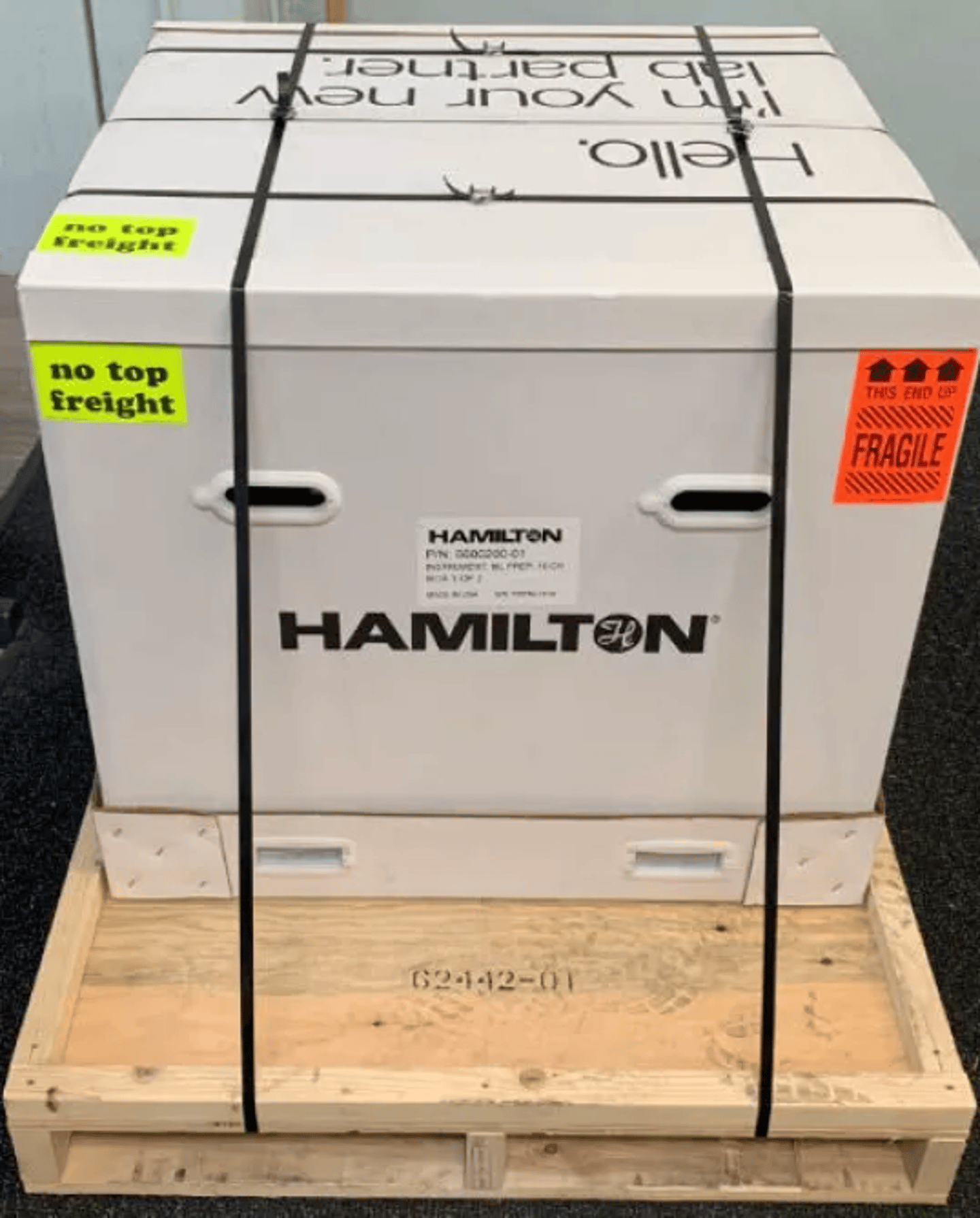 Hamilton-branded instrument shipping box on a wooden pallet, labeled "Fragile" and "No Top Freight"