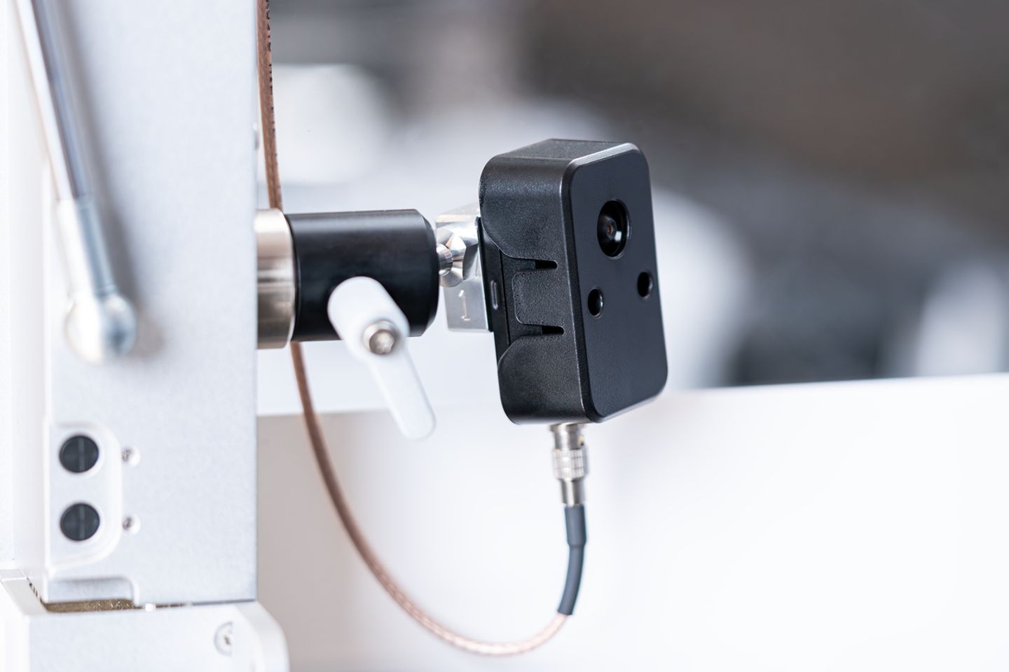 Small black rectangular camera module mounted on a rod clamp bracket, with cable connected at base