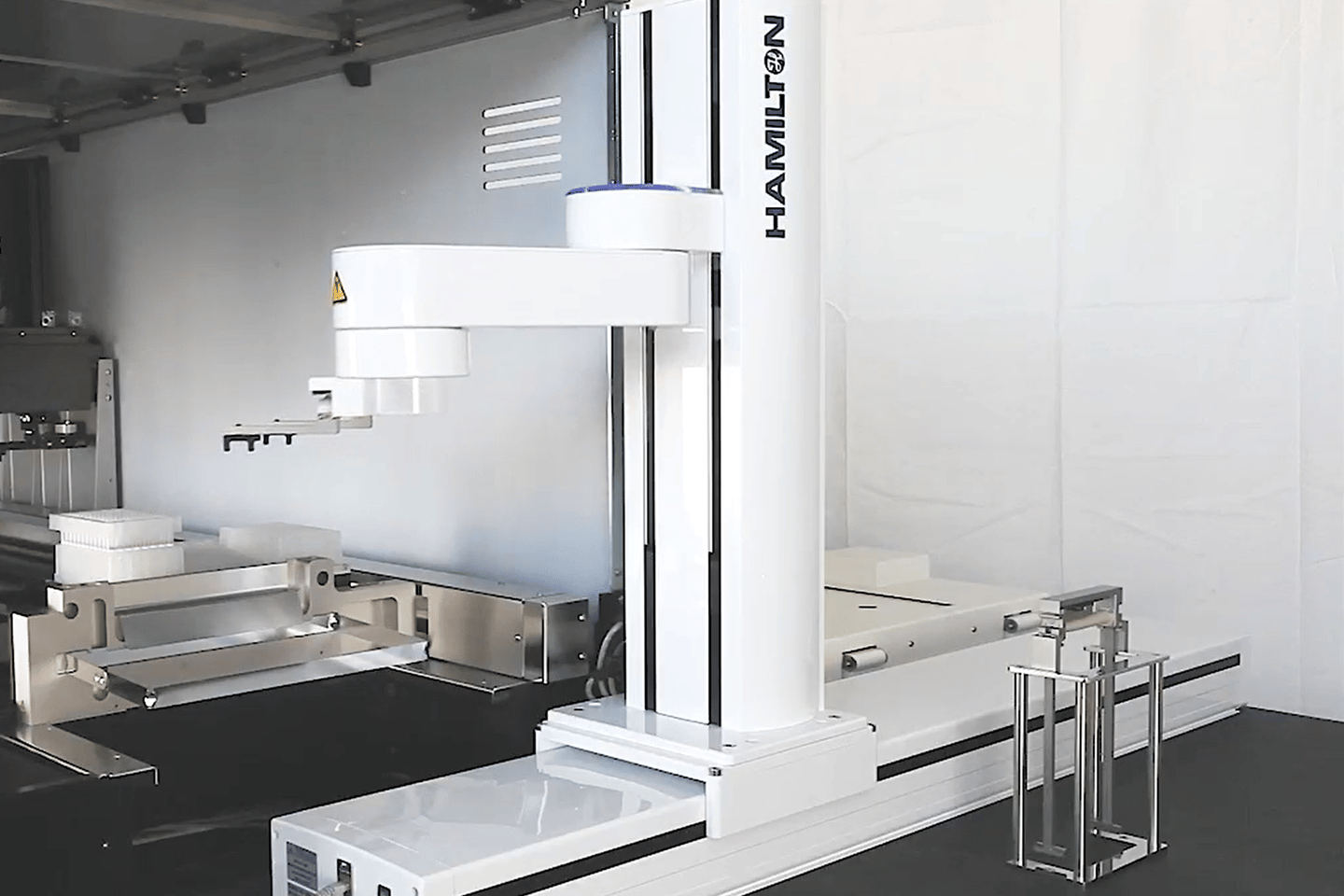 Hamilton robotic arm on vertical rail over an automated liquid handling deck with microplates and tip racks