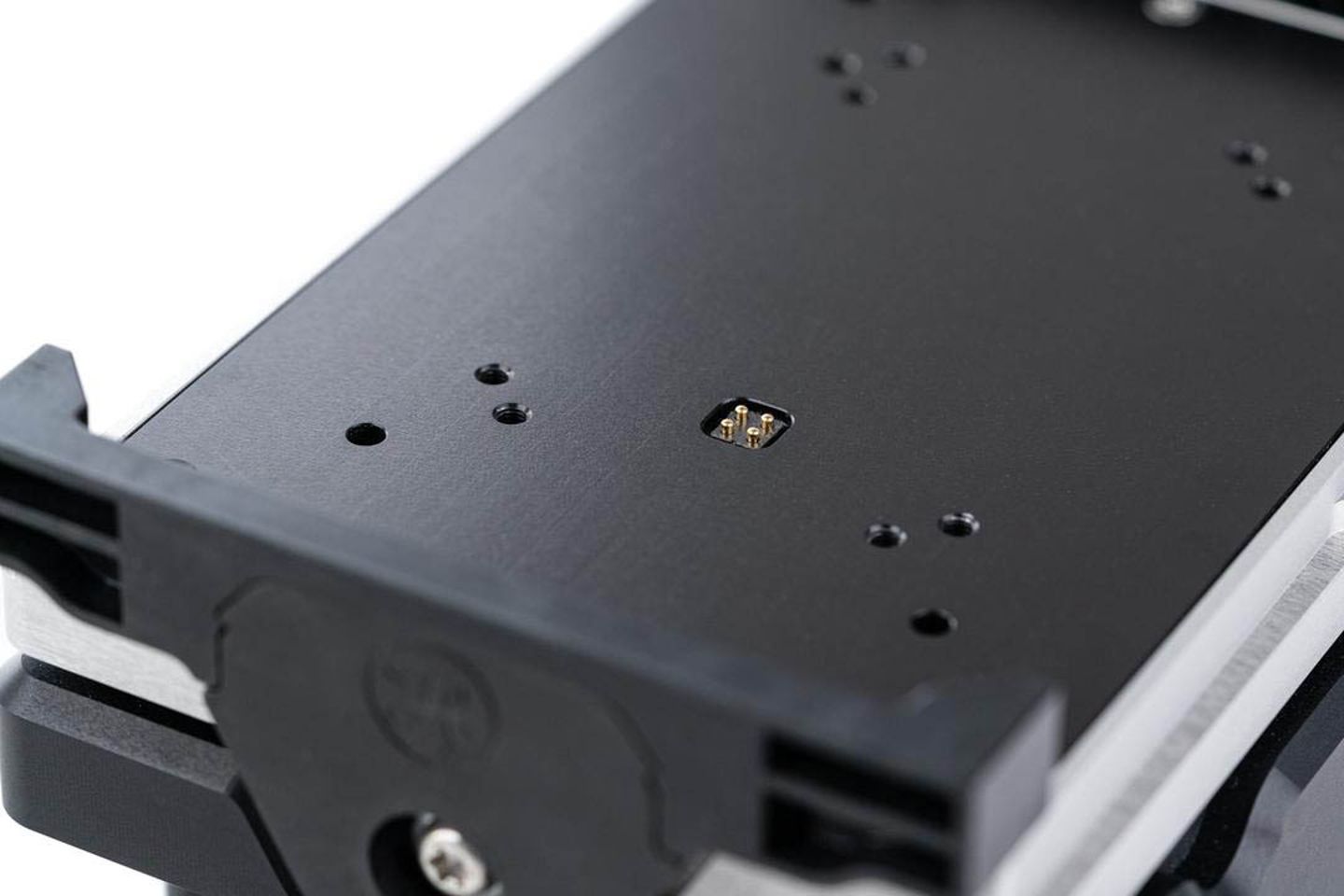 Close-up of a black anodized module plate with pogo pin connector and mounting holes on a precision instrument assembly