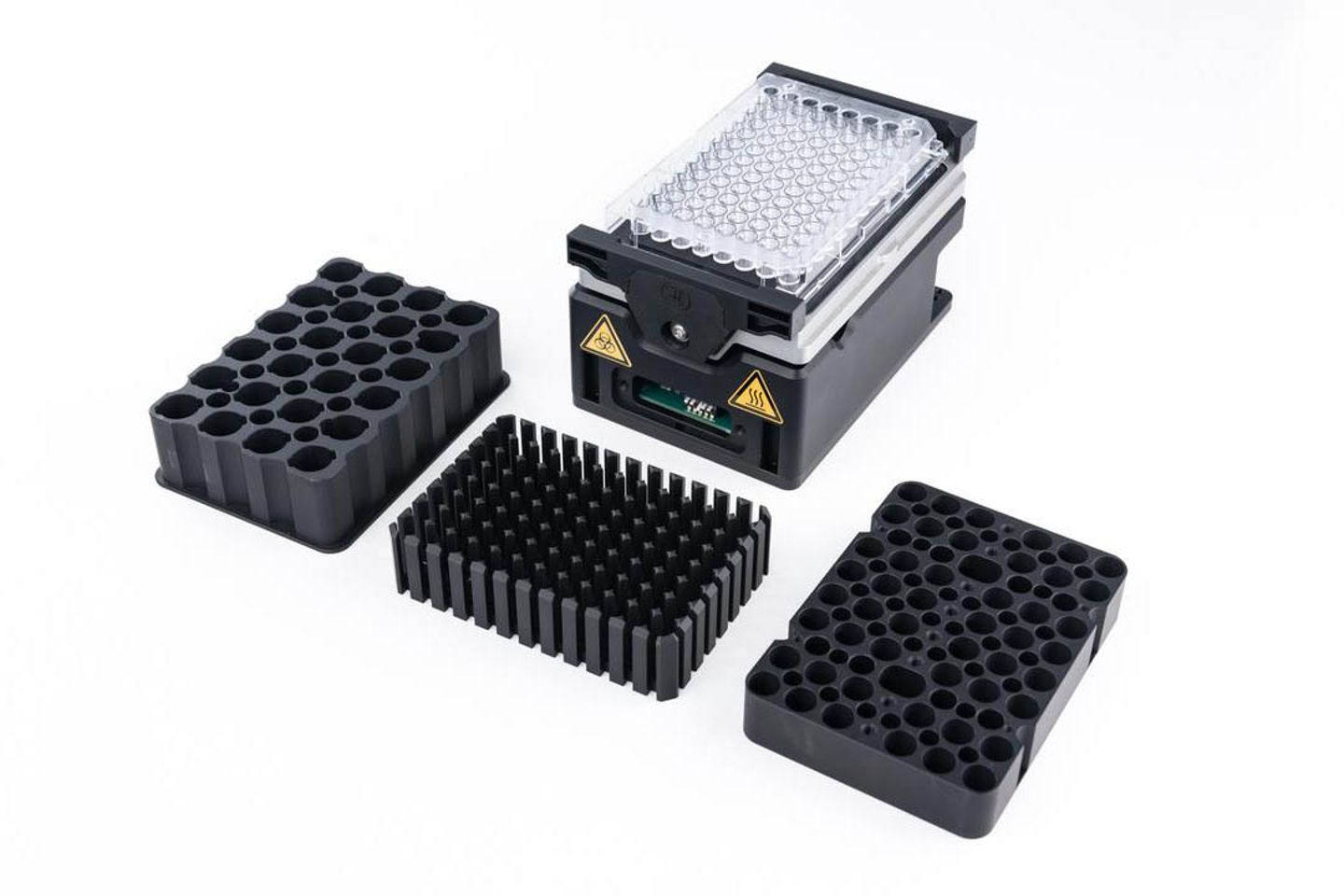 Modular heater/shaker unit with 96-well microplate, alongside three interchangeable block adapters on white background