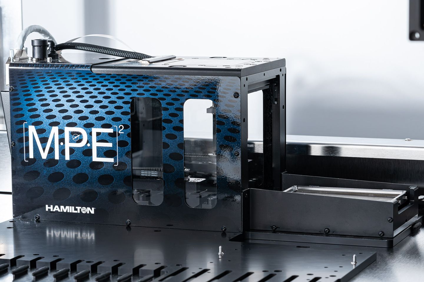 Hamilton MPE² module with blue perforated panel, transparent window, and open frame section on lab deck