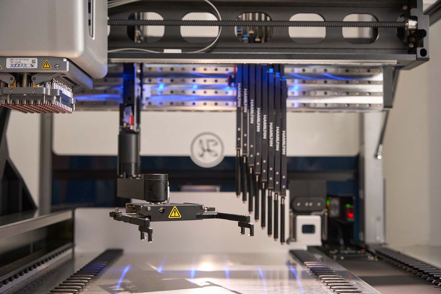 Hamilton automated liquid handler deck with 8 CO-RE pipetting channels and robotic arm under blue LED illumination
