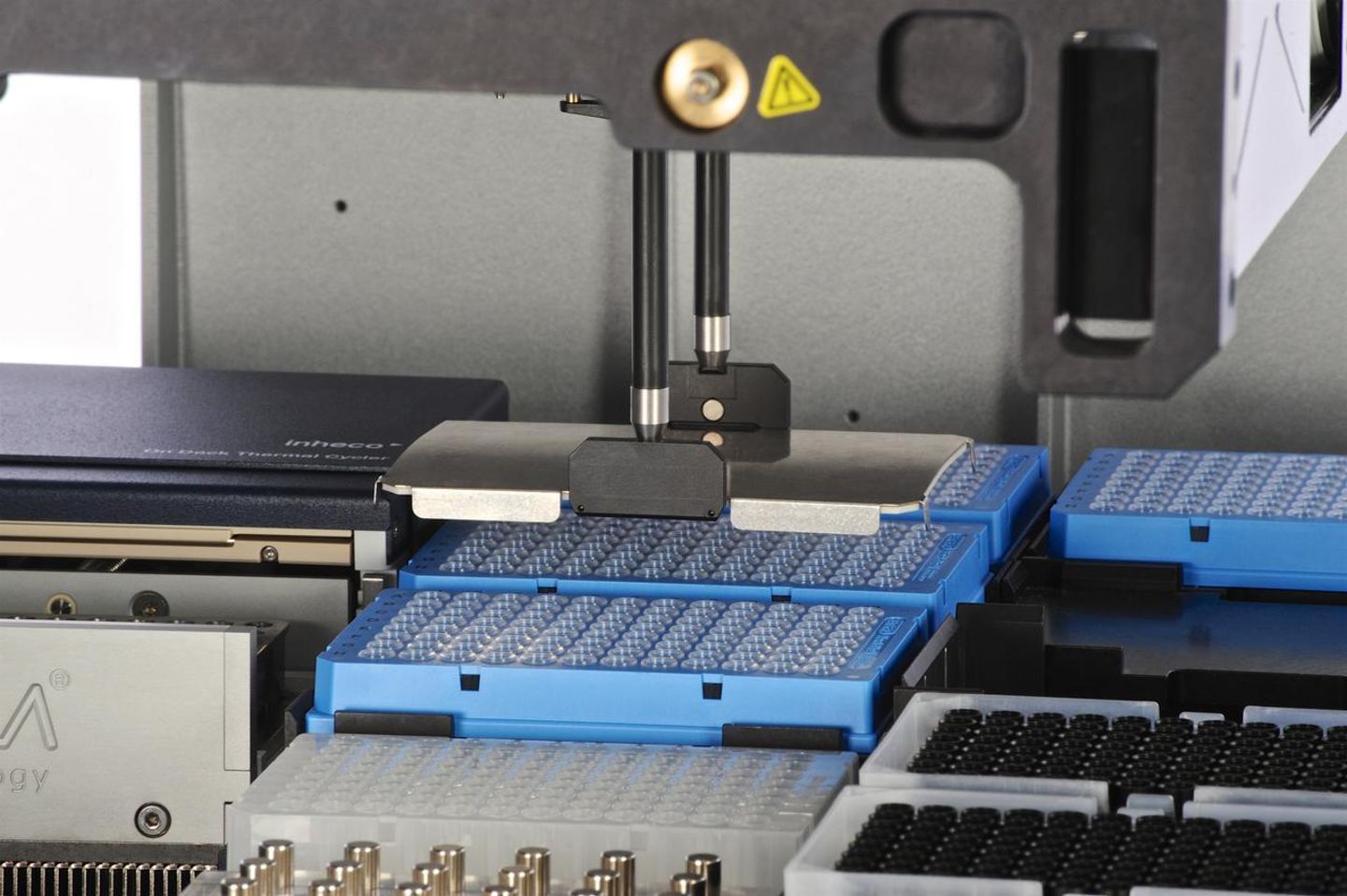 Robotic gripper arm holding a 384-well plate above stacked blue microplates on an automated liquid handling deck