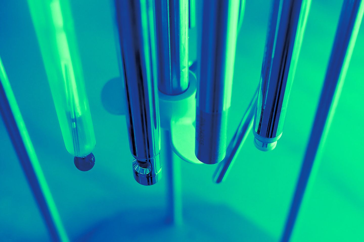 Close-up of multiple stainless steel sensor probes mounted in a cluster against a teal-lit background
