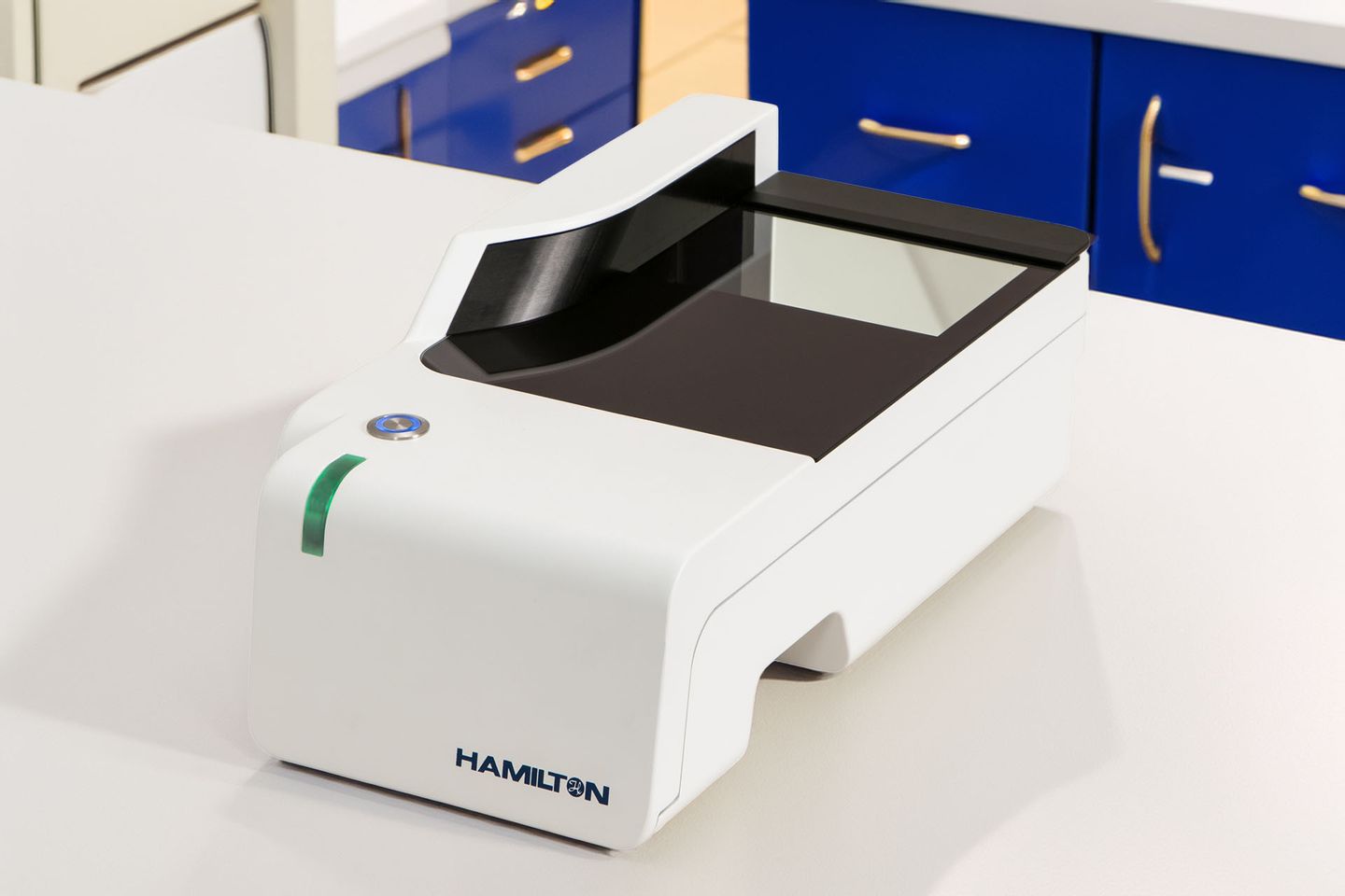 Hamilton-branded white benchtop label reader with open scanning bed, blue power button, and green status indicator