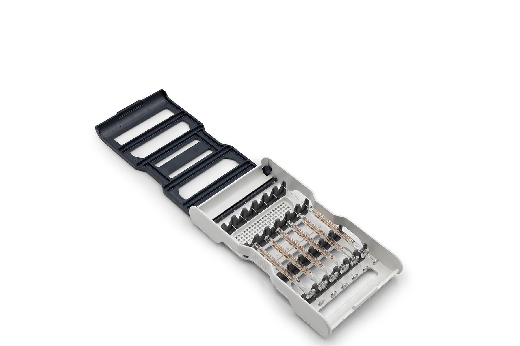 Open syringe tray with multiple syringes secured in holder, alongside a dark slotted lid