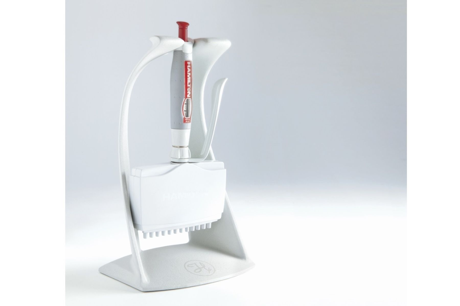 Hamilton multichannel pipette resting in a white stand with tip box storage at the base