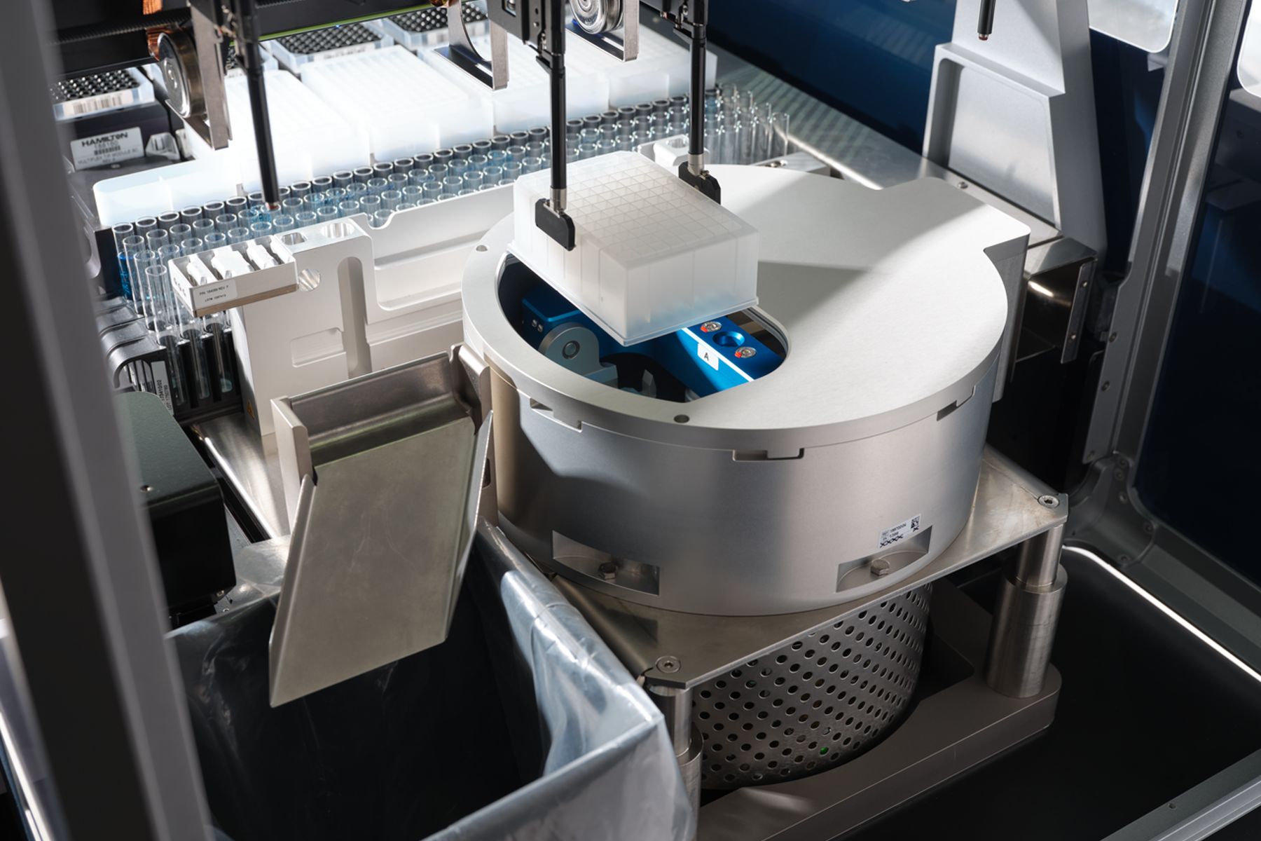 Automated liquid handler pipette heads positioned over a centrifuge with a microplate loaded on its rotor