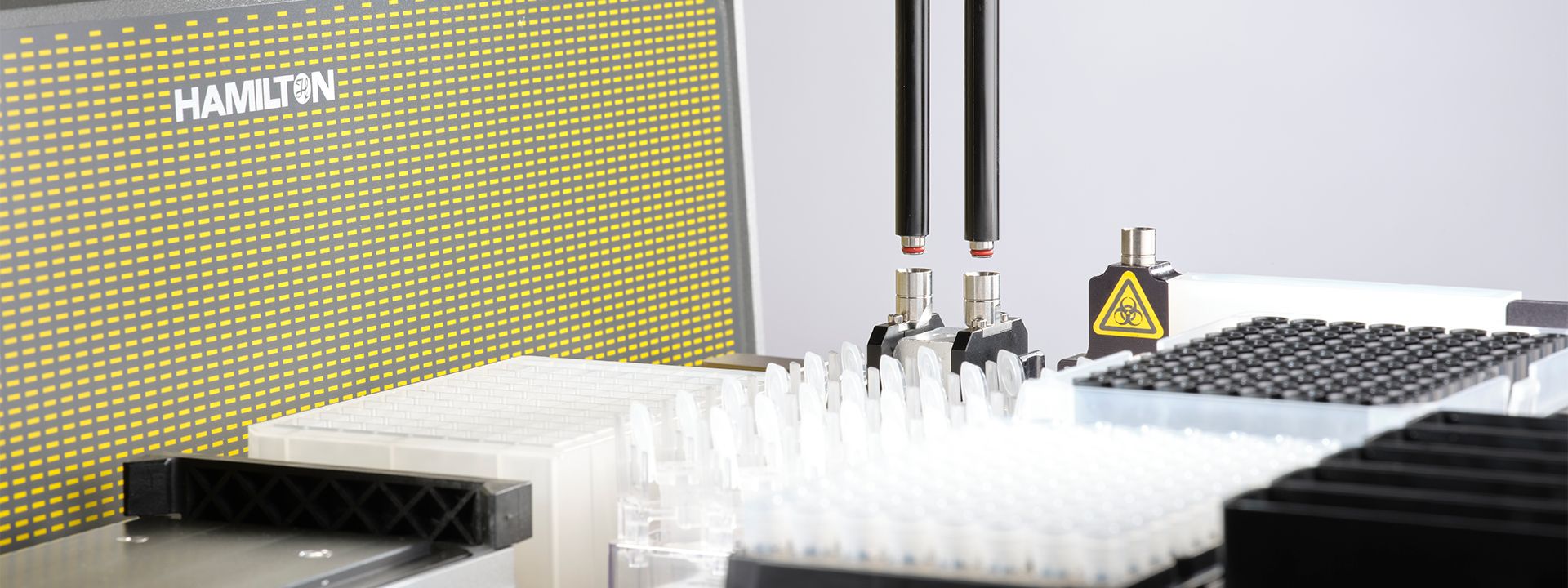 Hamilton automated liquid handler pipette arm with dual CO-RE gripper tools positioned over white tip racks