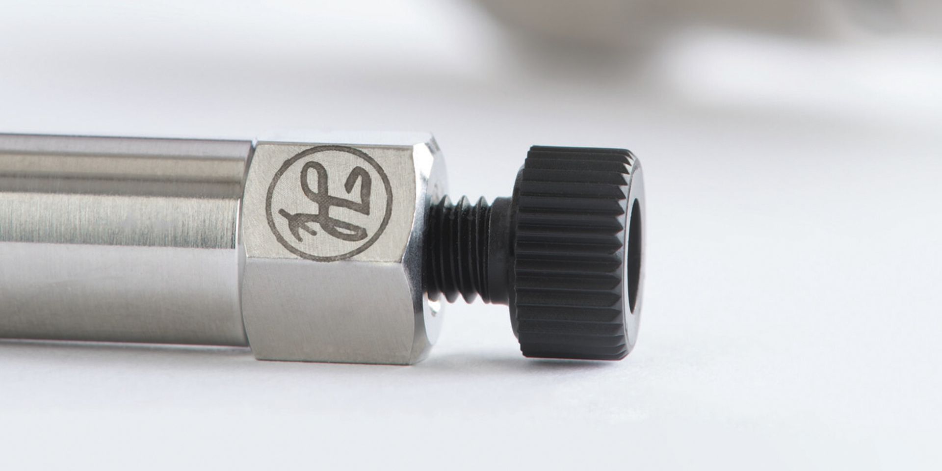 Close-up of a stainless steel HPLC column with hex-head fitting and black knurled end cap