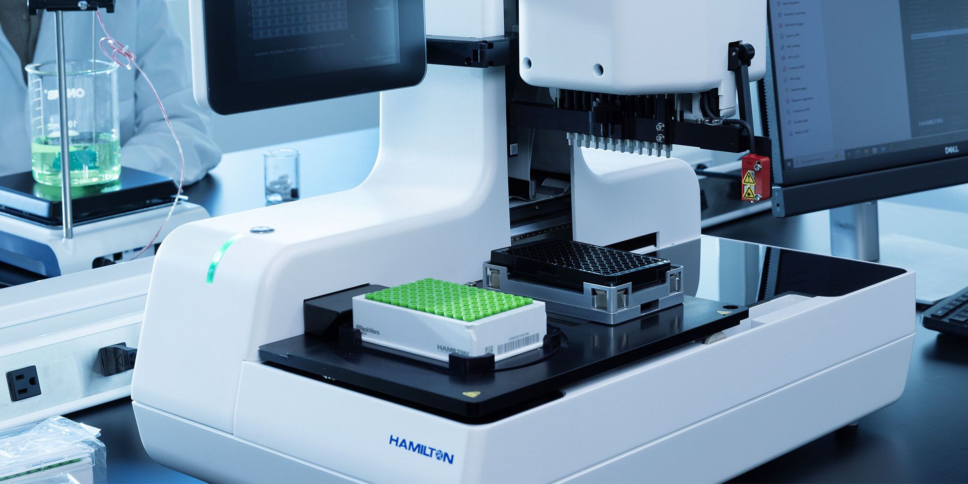 Hamilton automated liquid handler with green-capped sample rack and microplate on deck, laboratory setting