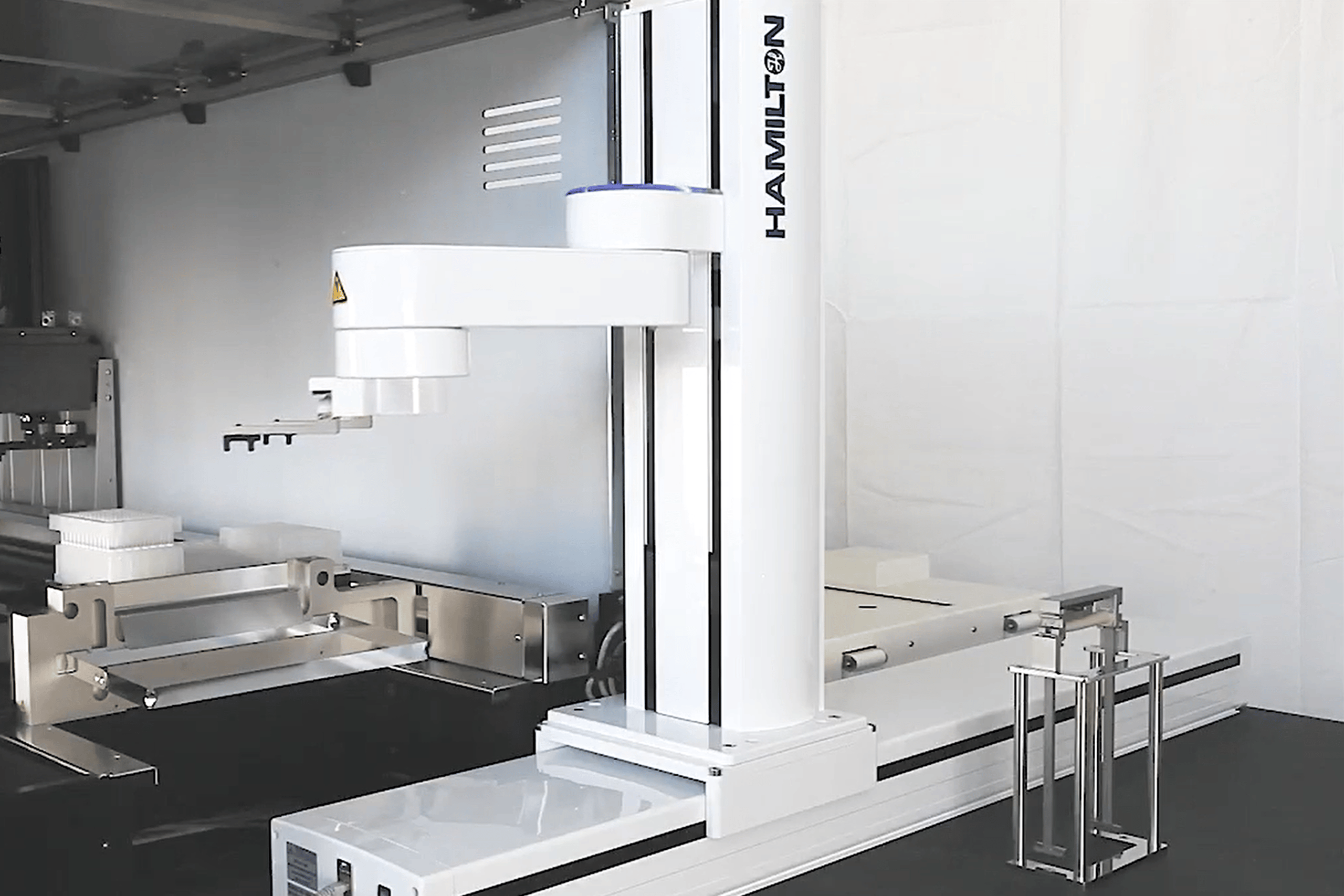 Hamilton robotic arm on vertical rail over an automated liquid handling deck with microplates and tip racks