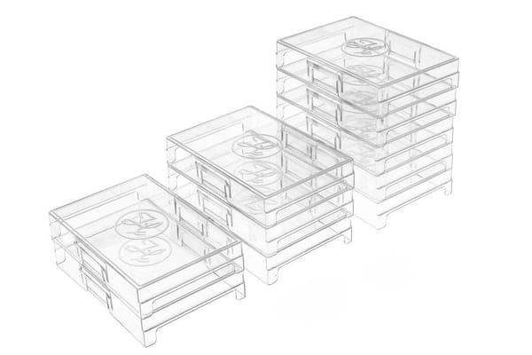 Three stacks of clear plastic storage trays arranged in ascending heights, each with circular embossed lids