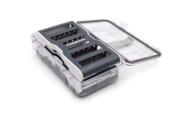Hamilton Syringe Guard Kit in an open clear protective case with dark gray and white body, multiple slots visible