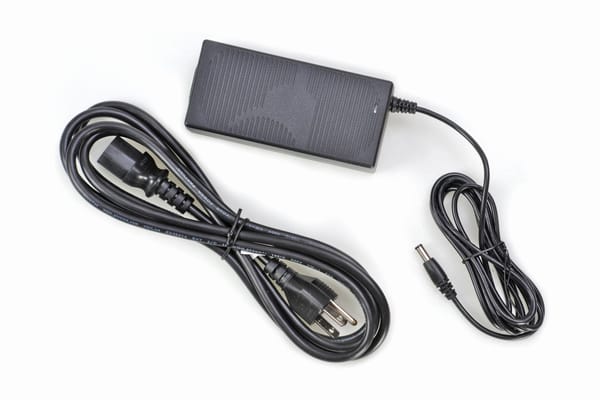 Black AC power adapter brick with detachable power cord and DC barrel connector cable on white background