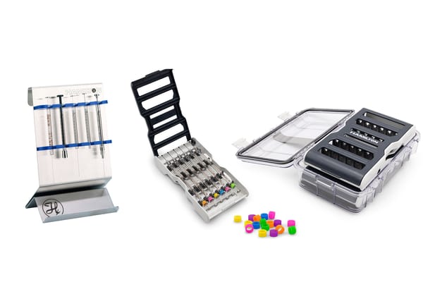 Hamilton syringes in colorful collar rings, a metal syringe stand, an open multi-syringe tray, and a sealed storage case