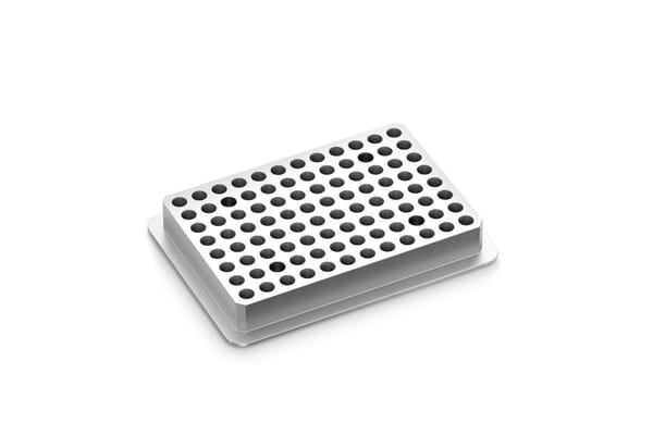 White rectangular 96-well PCR adapter block with black-lined wells, angled view