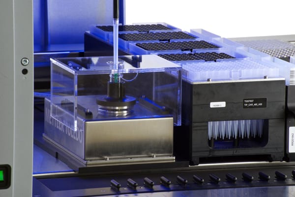 Automated liquid handler dispensing into a Mettler Toledo balance, with tip carrier and microplate rack visible
