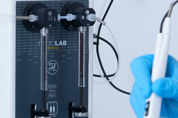 Hamilton microLAB 500 Series dual-syringe diluter with tubing and a gloved hand holding a probe