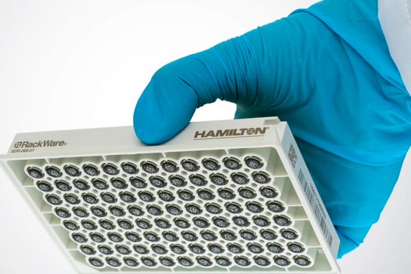 Gloved hand holding a Hamilton RackWare SDR-096-01 sample storage rack with 96 barcoded tube positions