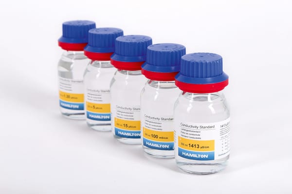 Five Hamilton conductivity standard bottles (300 ml) labeled 1413 µS/cm, 100 mS/cm, 15 µS/cm, 5 µS/cm, arranged in a row.
