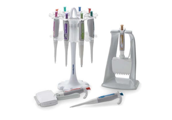 Hamilton pipette stands holding single-channel and multichannel pipettes, with two pipettes lying flat in foreground
