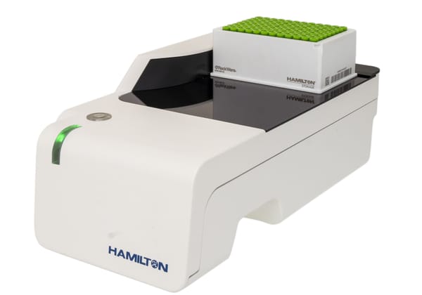 Hamilton ID reader with a Hamilton Storage RackWare tube rack loaded on its scanning platform, green-capped sample tubes visible on top