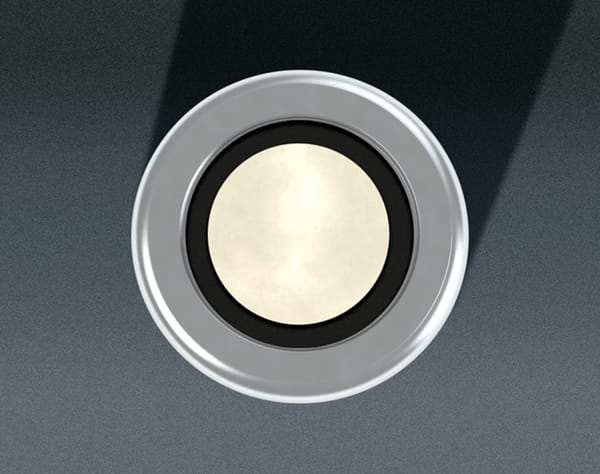 Close-up of a circular sensor with a polished metallic disk, black ring, and chrome bezel