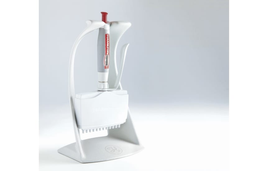 Hamilton multichannel pipette resting in a white stand with tip box storage at the base