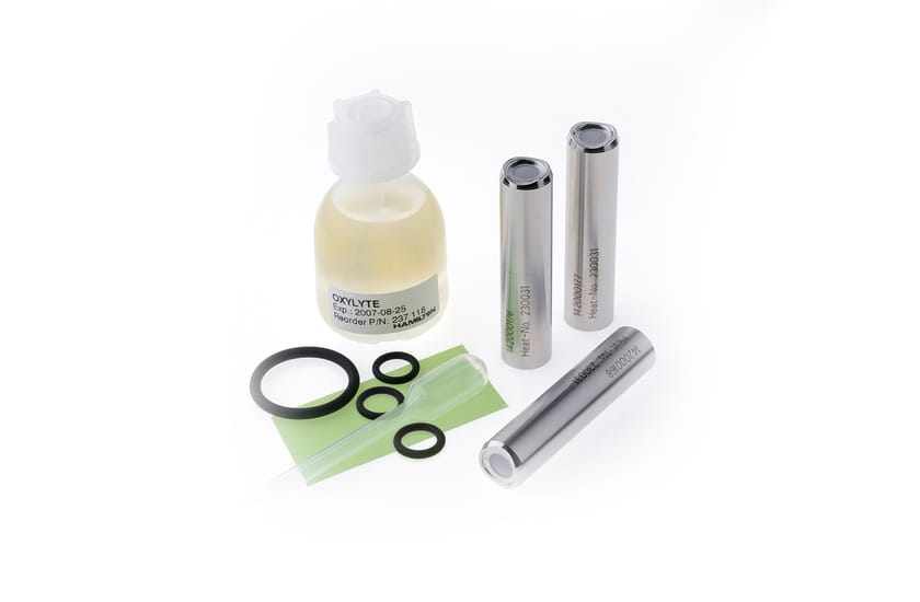 Oxylyte solution bottle, three stainless steel membrane caps, O-rings, and a small spatula on white background