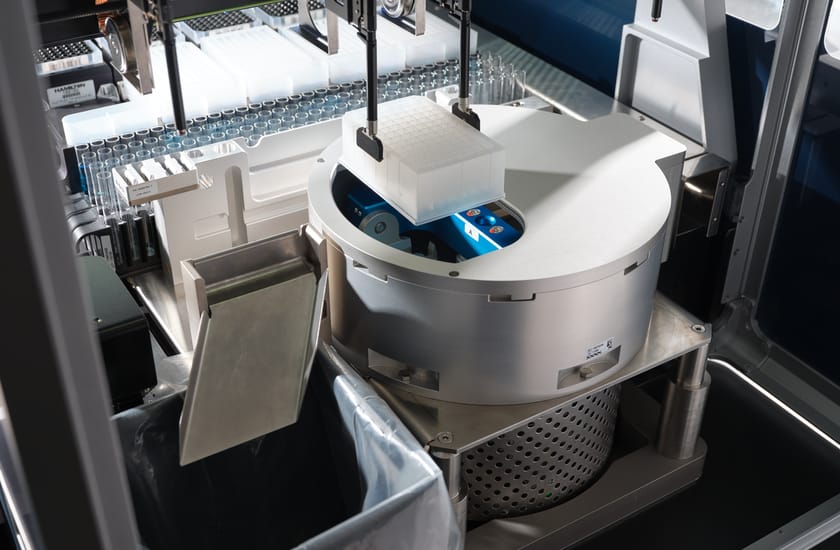 Automated liquid handler pipette heads positioned over a centrifuge with a microplate loaded on its rotor